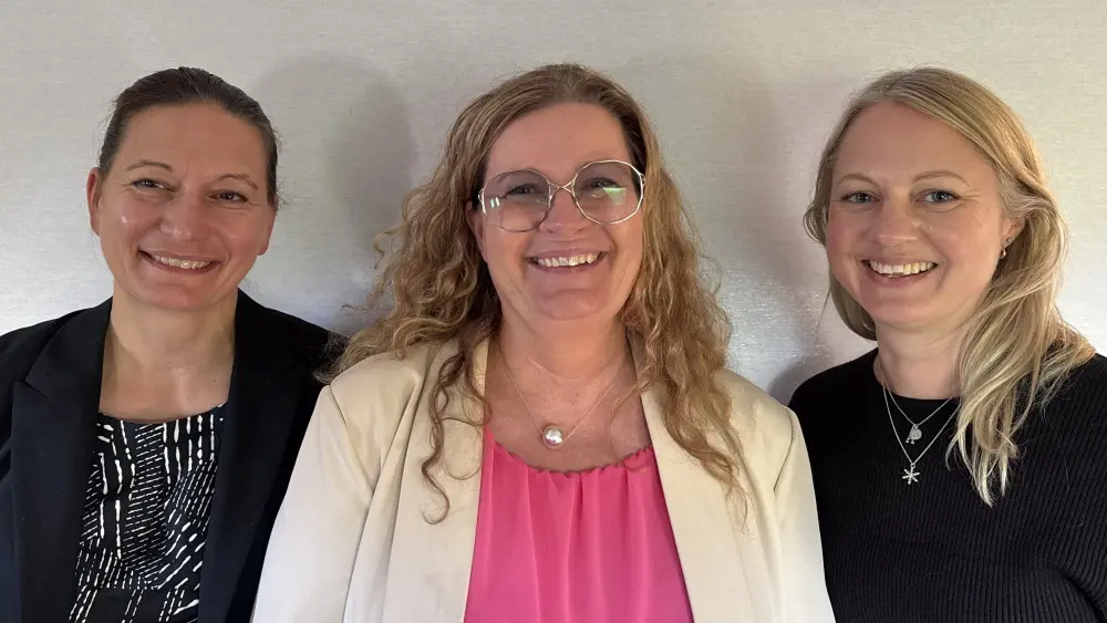 Tre leende personer som tittar in i kameran.