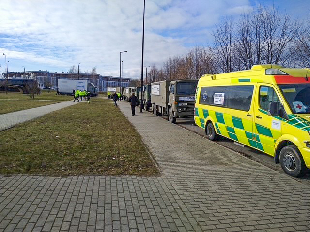 En konvoj med militärfordon och en ambulans på en väg i Ukraina.