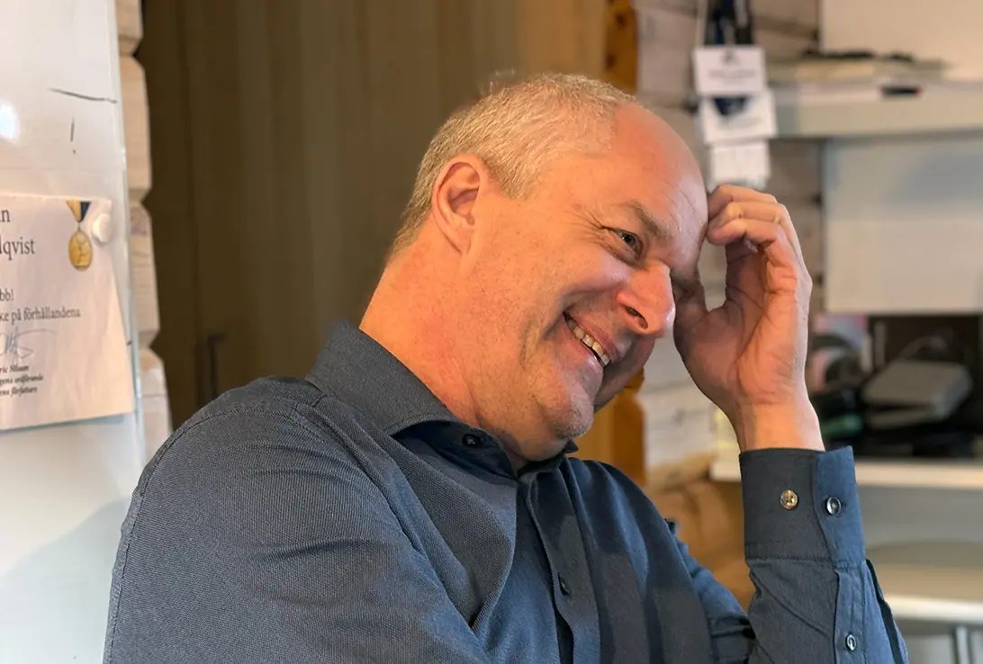 En leende man som lutar huvudet i sin hand