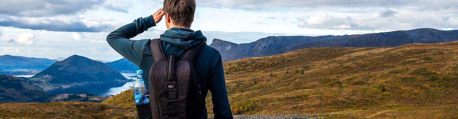 Person som står med ryggen mot kameran och blickar ut mot ett fjällandskap