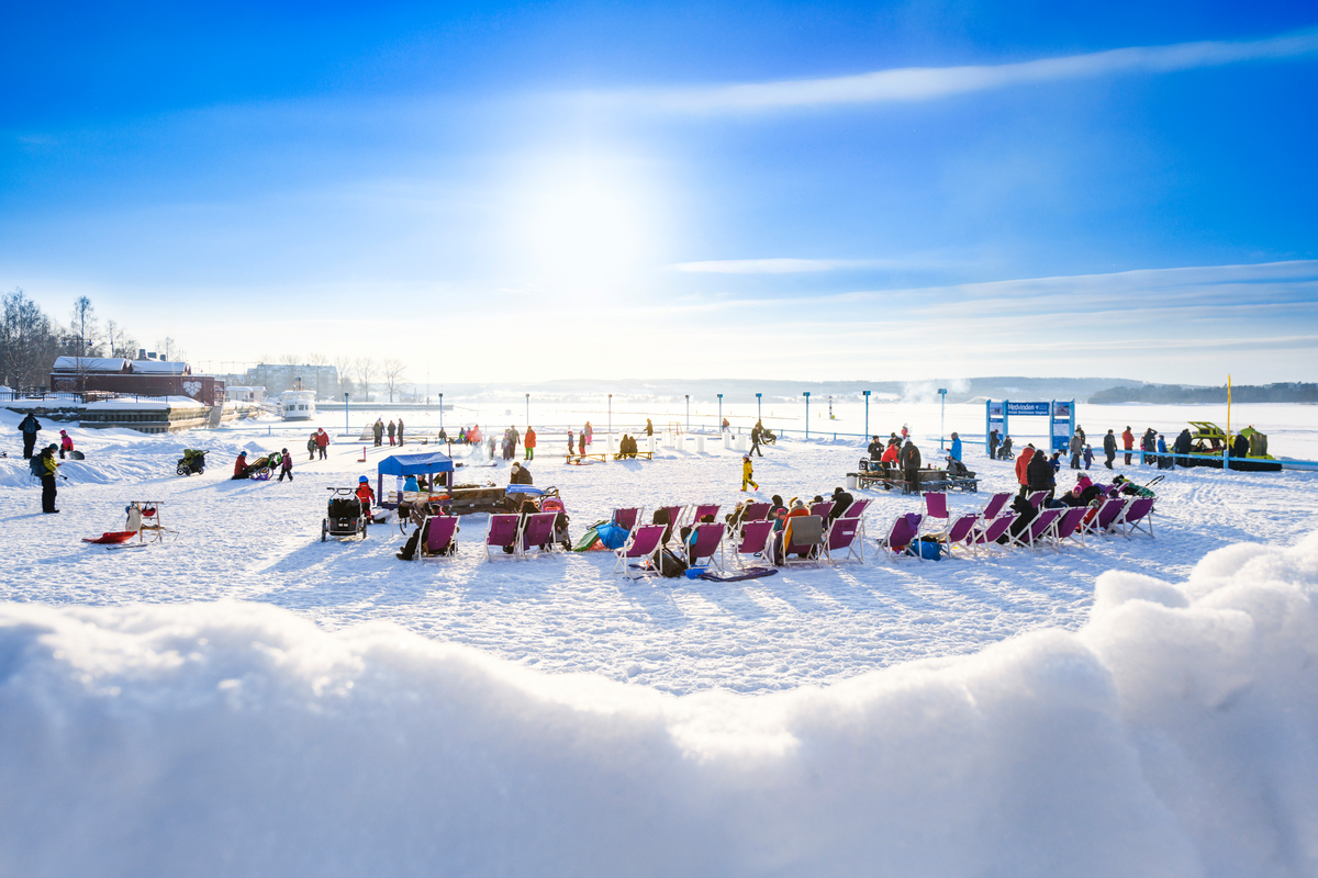 Bild på personer som sitter i solstolar på isen i Vinterparken, Östersund