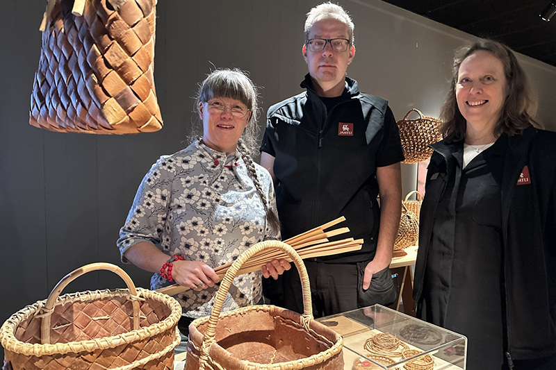 Tre personer står intill varandra och någon håller en flätad korg i händerna