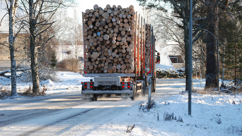 Timmerbil som kör på vintrig gata, bort från kameran.