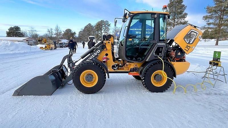 Skogsmaskin lastar timmer på ett släp.