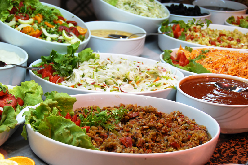 Ett uppdukat buffébord med olika skålar av köttfärs, sallad och grönsaker, samt pasta och såser.