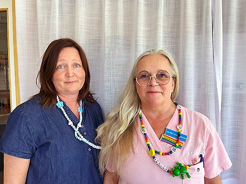 Två kvinnor som tittar in i kameran och ser glada ut.