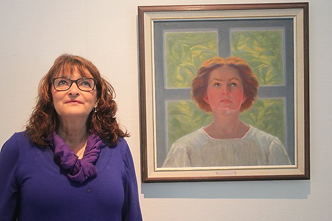 En kvinna, Ellen Hyttsten, står intill en målning av en kvinna. Båda blickar upp i fjärran.