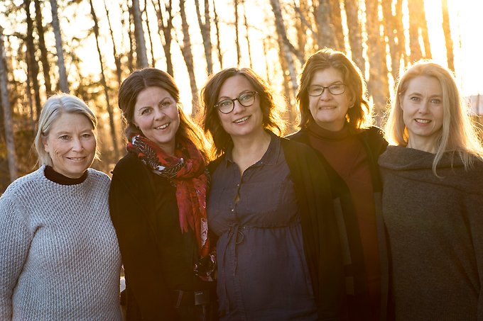 fem kvinnor står utomhus i motljus