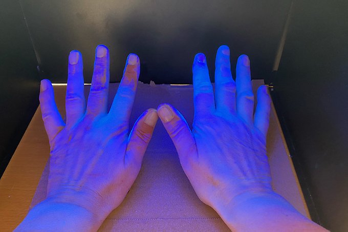 Ett par händer belyses med blått ljus