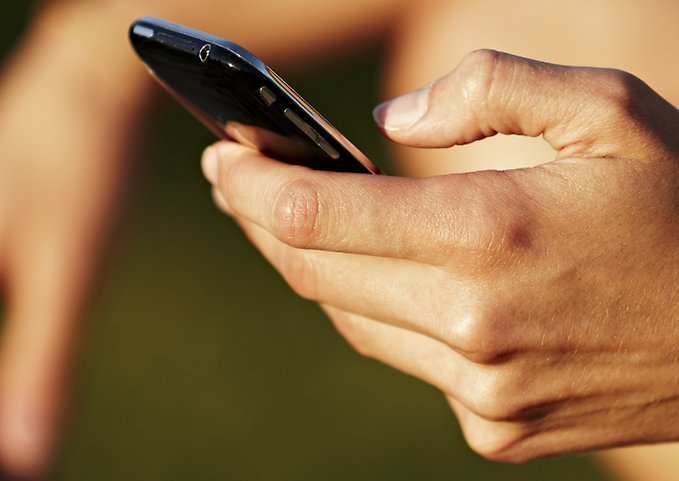 Närbild på en hand som håller i en smart mobiltelefon. 