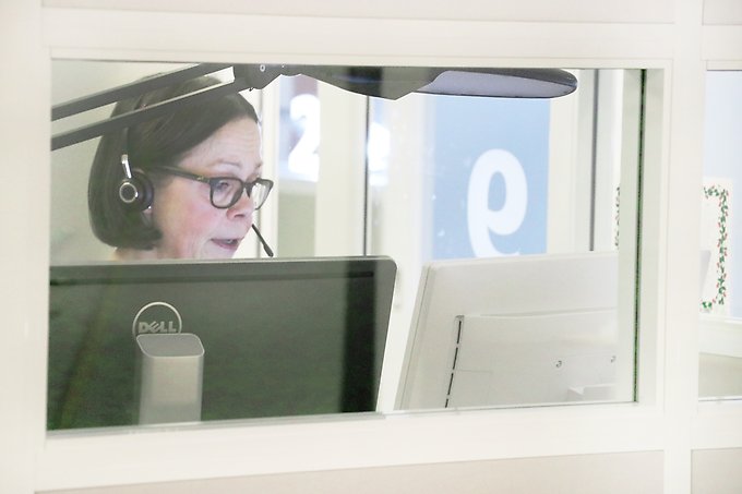 en person med headset på sig framför två datorskärmar